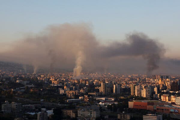 Large plumes of smoke rise over a city.