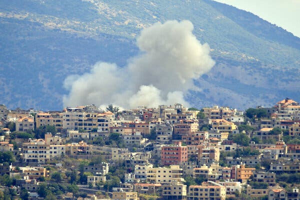 Smoke rises from behind a hillside scene of apartment buildings.