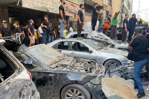 Men stand on a row of cars covered in dust and rubble.