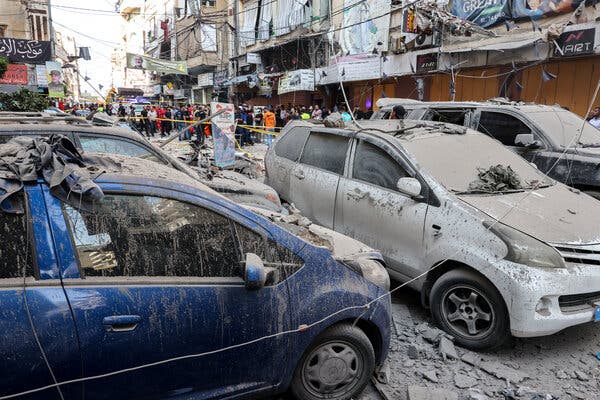 Damaged cars covered in dust and debris in a dense, urban area.