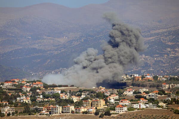 Dense gray smoke rises over a cluster of buildings.