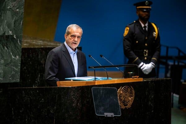 Masoud Pezeshkian, in a suit with an open-necked blue shirt, speaking from a U.N. podium.