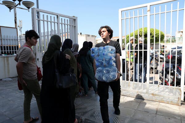 A young man carries bottles of water through a gate. 