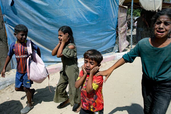 Four children walking together and crying. They have dirt on their faces, and two are holding their hands over their ears.