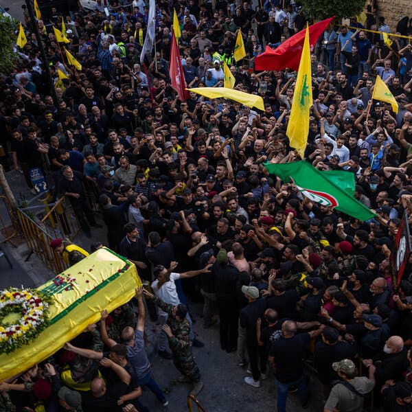 A crowd of people holding flags and carrying a coffin.