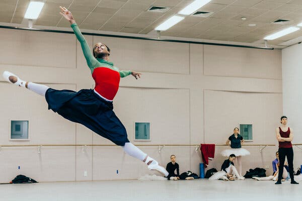 Michaela DePrince, her arms outstretched, leaps in the air at a dance studio as half a dozen other dancers look on.