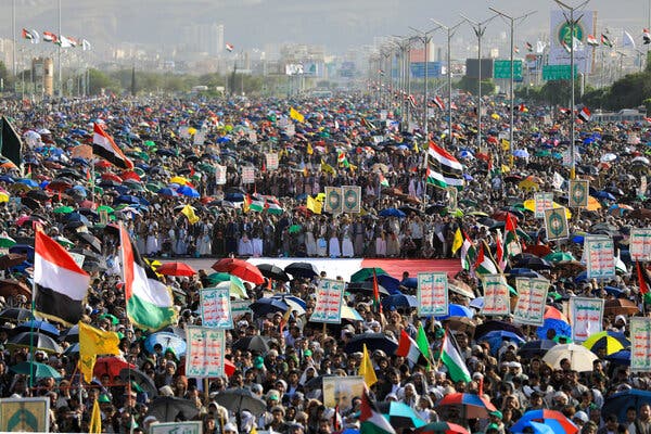 Thousands of people crowd into an area holding signs and flags.