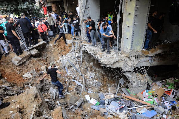 Several people climb in and around a badly damaged building.