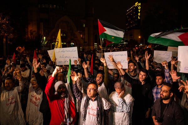 A crowd of people waving signs and flying Palestinian flags.