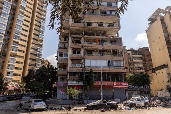 A multistory residential building with rubble below and damage to upper floors.