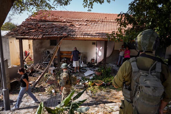 Security forces and residents inspecting a damaged house.