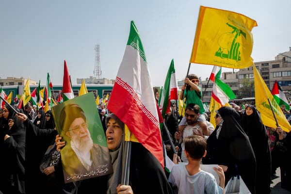 Demonstrators hold up many flags in a gathering outside.