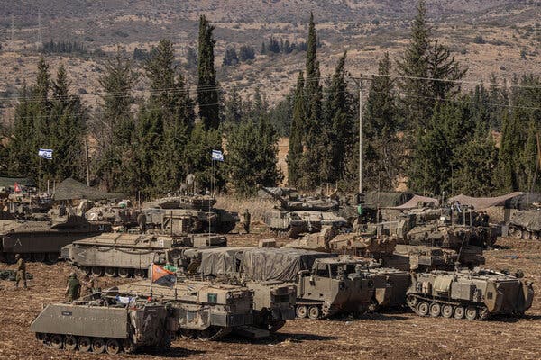 Tanks and armored vehicles, some with Israeli flags on them, in a field in northern Israel.