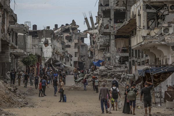 A street is surrounded by rubble and bombed out buildings. 