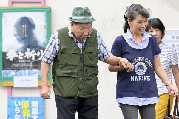 A woman walks hand in hand with an elderly man.