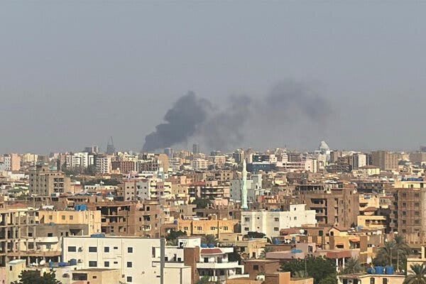 Smoke billows into the sky above a city packed tight with buildings.