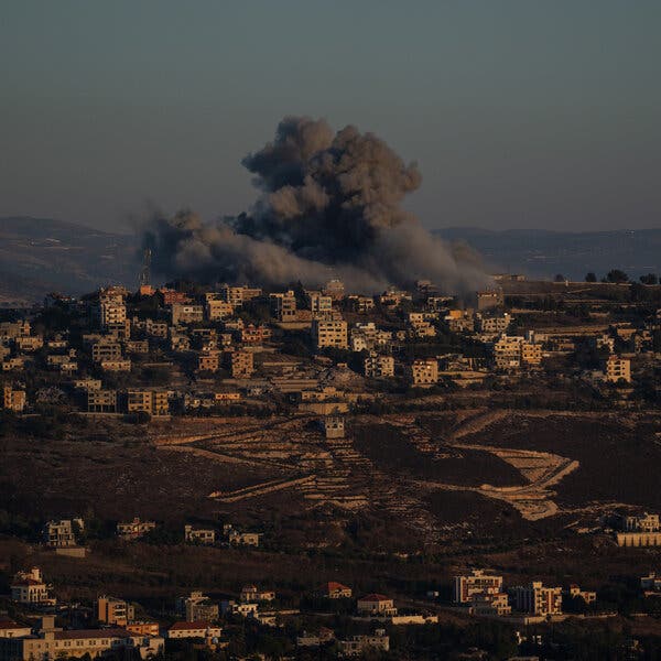 A large dust cloud above buildings on a hillside.