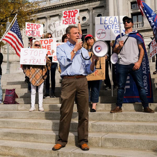 Representative Scott Perry of Pennsylvania holding a megaphone and standing on steps in front of a Stop the Steal rally.