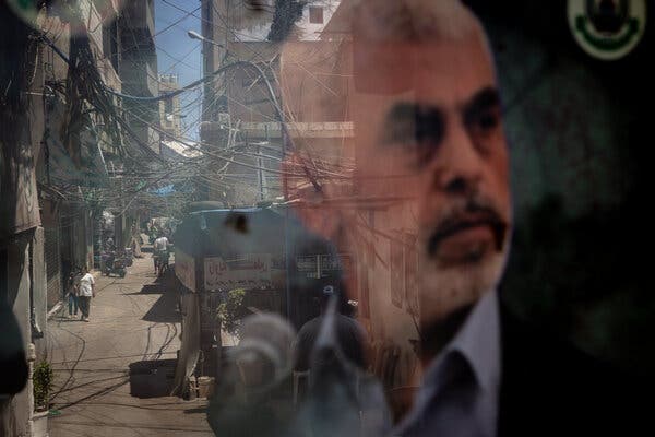 A poster of Yahya Sinwar can be seen in a window that is also reflecting a street scene.