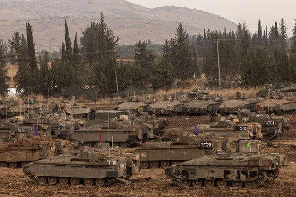 Tanks fill an open area lined with trees. 