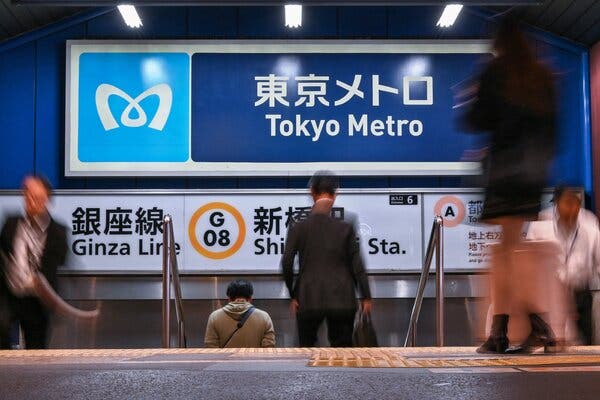 Several people walking up and down steps at a Tokyo Metro station.