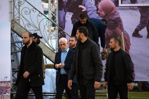 The Hamas leader wearing a suit coat, with several other men around him.