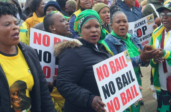 A group of women standing together outside and one holding a sign that reads, ‘no bail.’