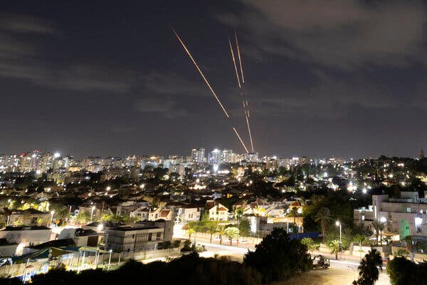 Trails of light appear in the night sky over a city.