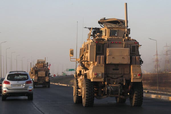 A pair of large military vehicles driving down a road.