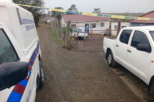 A home seen behind caution tape and between a white truck and emergency response vehicle.