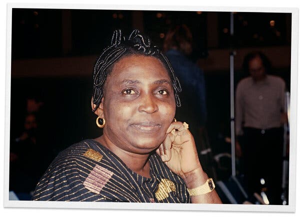 A portrait of Mariama Bâ wearing a patterned outfit and smiling slightly at the camera, her left hand resting on her cheek.