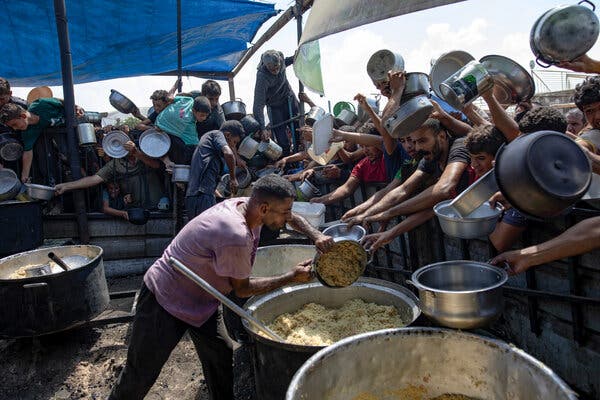 People crowd around an outdoor kitchen.