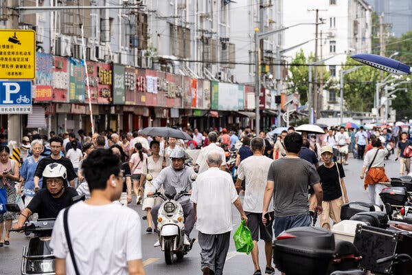 Pedestrians, produce shoppers and motorbike riders crowding a Shanghai street.