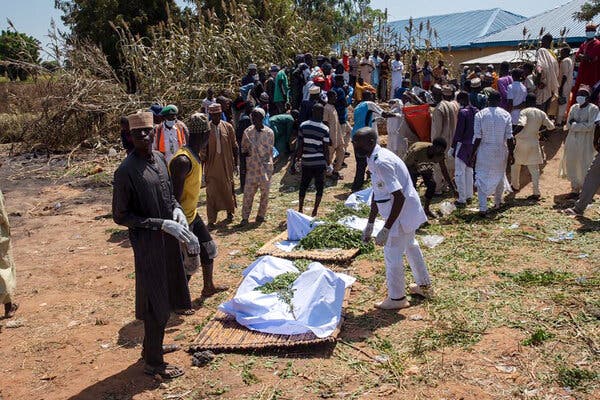 A group of people stand around several shrouded bodies after a fuel tanker explosion in Nigeria.