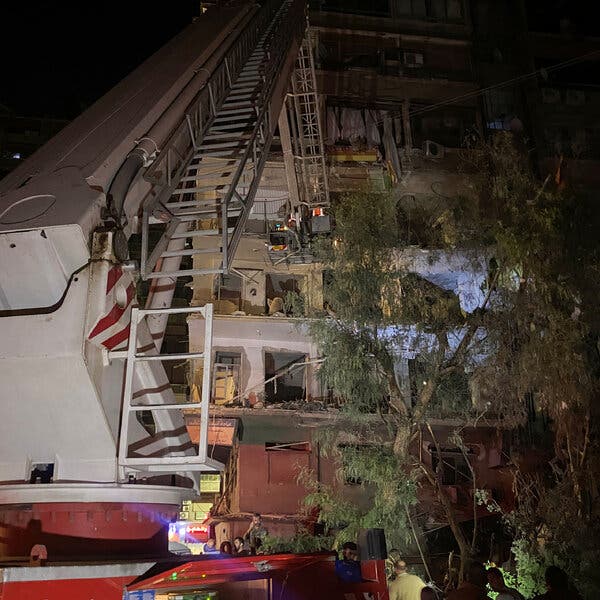 A large crane next to a damaged building.