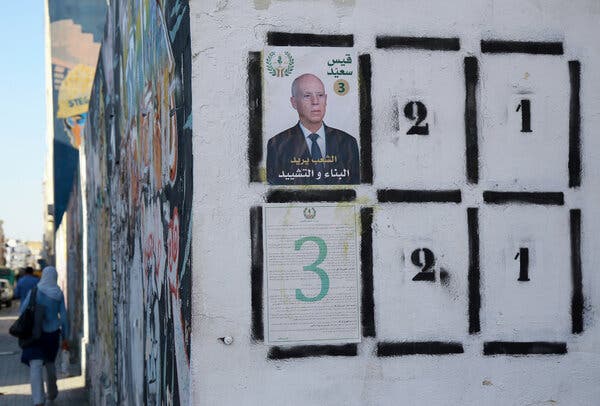 A small poster on a white building shows a man’s face.