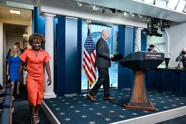 President Biden stepping to a lectern. An American flag is displayed behind him.