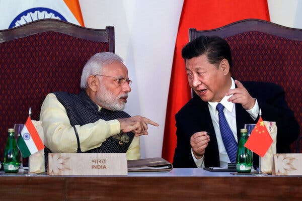 Narendra Modi and Xi Jinping lean toward each other in conversation.