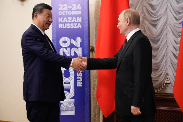 The leaders of China and Russia shaking hands near a sign that says ”BRICS.”