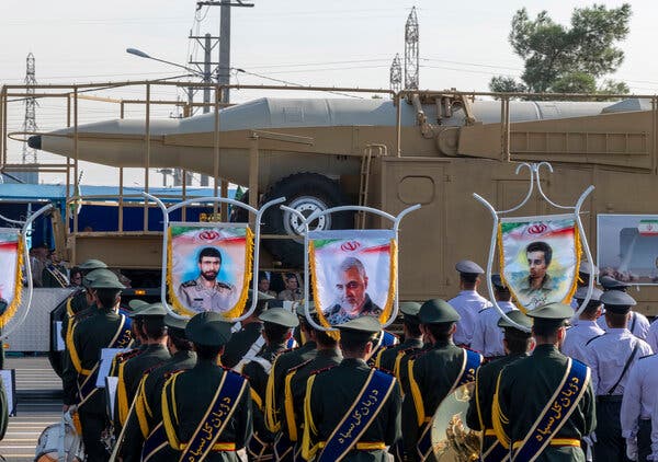 A large missile is carried out past columns of soldiers and portraits of people. 