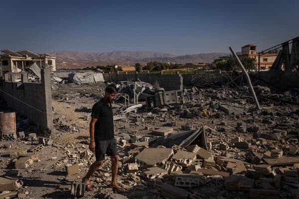 A man in shorts and a black T-shirt walks through the rubble of a building in Hilaniyeh, Lebanon.