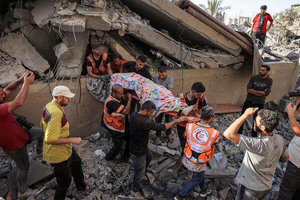 Rescue workers wearing orange reflective vests carry a body on a stretcher.