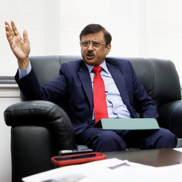 Sanjay Kumar raises his hand while seated in a chair.