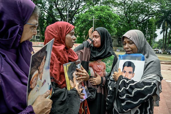 A group of women, each holding photos of their missing loved ones.