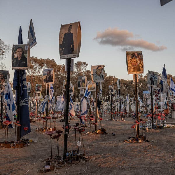 An outdoor memorial with pictures of people and several Israeli flags.