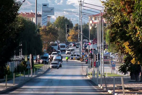 A street scene shot from a distance, showing police vehicles and a company sign.