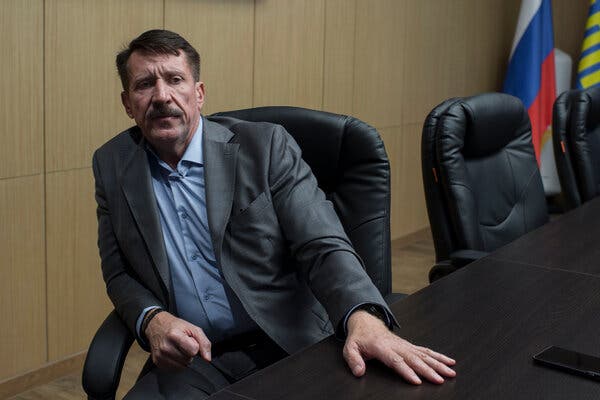 Viktor A. Bout sitting in a leather armchair with his hand on a table.