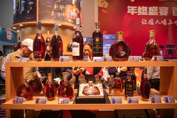 People stand behind shelves with bottles of brandy on display. 