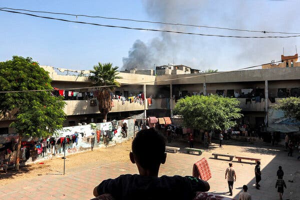 Smoke rising over the courtyard of a building where clothes are hanging.