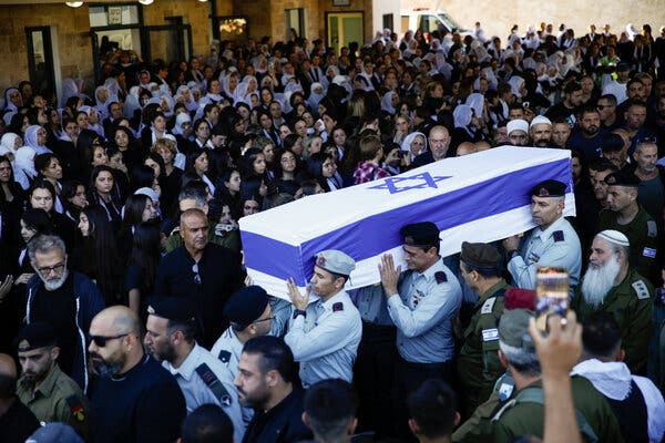 Soldiers carry a coffin covered in an Israeli flag through a crowd of mourners. 